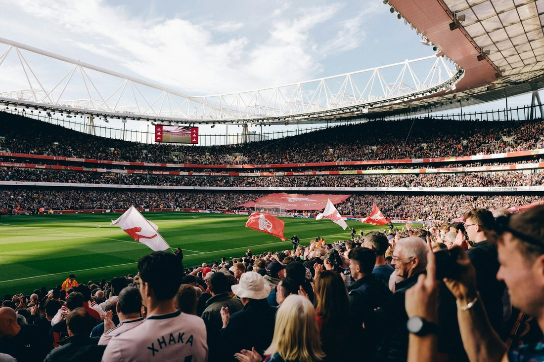 A packed stadium of football fans waving flags before kickoff, the atmosphere that makes a World Cup match day worth the trip