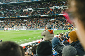 Fans fill a stadium and cheer during a packed football match 