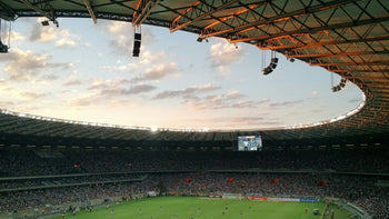 Fans fill an open-roofed football stadium at dusk
